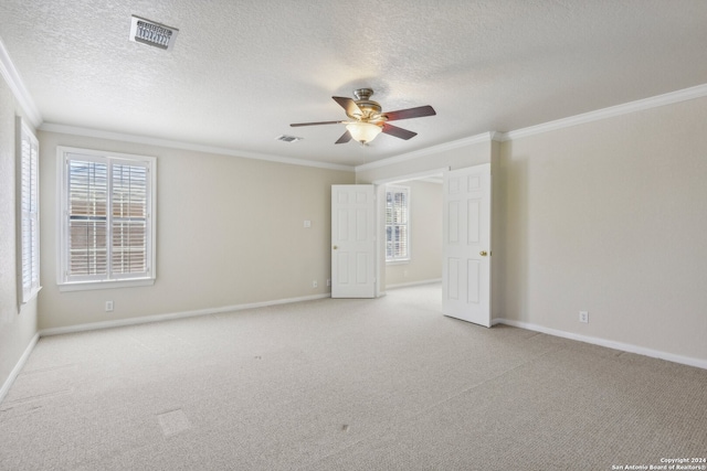 spare room with ceiling fan, light colored carpet, a textured ceiling, and crown molding