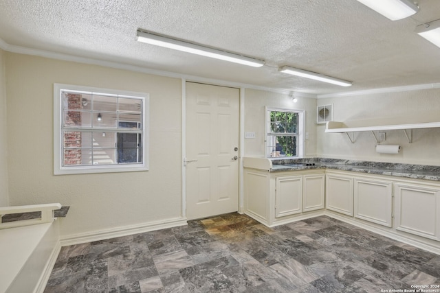 kitchen featuring white cabinetry, a textured ceiling, and crown molding