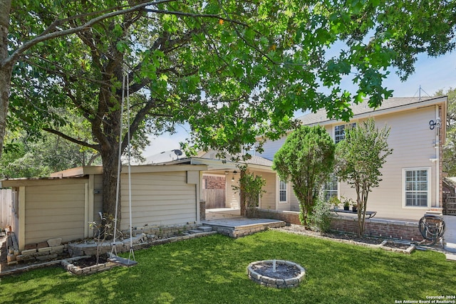 rear view of property featuring a fire pit, a lawn, and a patio