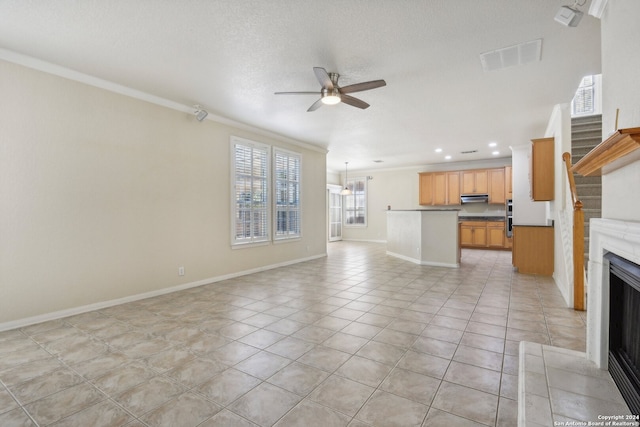 unfurnished living room with ceiling fan, a textured ceiling, light tile patterned floors, and crown molding