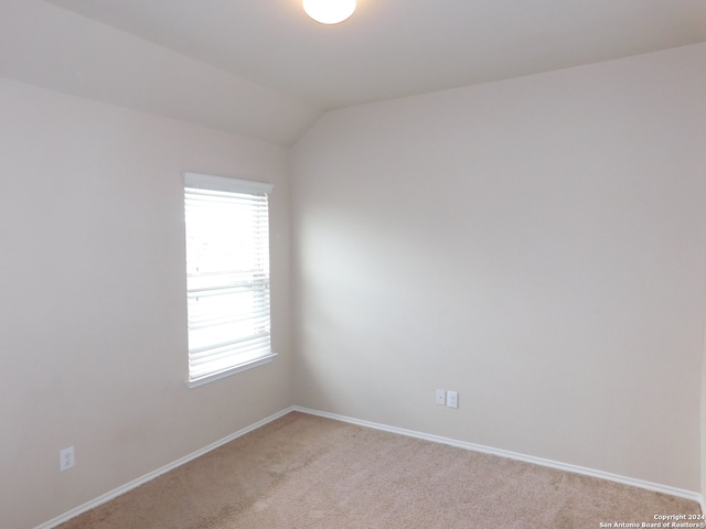 carpeted spare room with vaulted ceiling