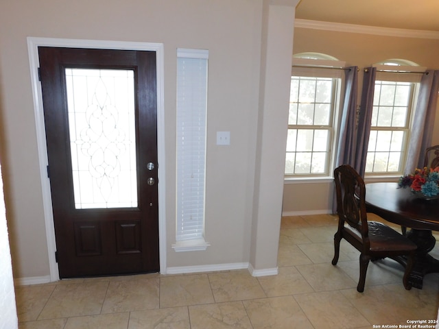 entryway with a wealth of natural light, crown molding, and light tile patterned flooring