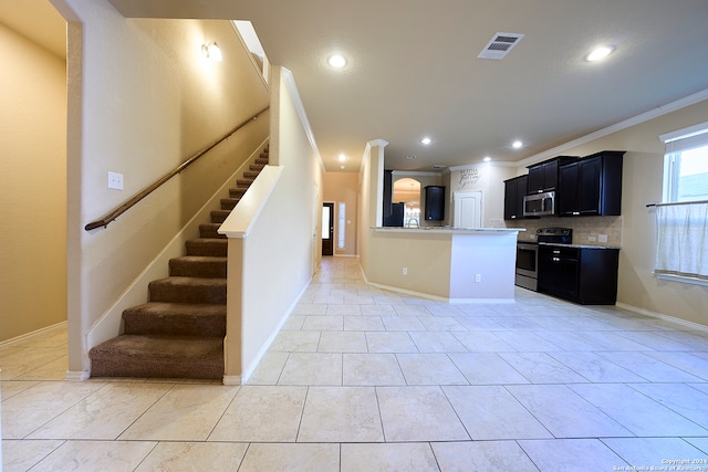 kitchen featuring backsplash, kitchen peninsula, appliances with stainless steel finishes, light tile patterned floors, and ornamental molding