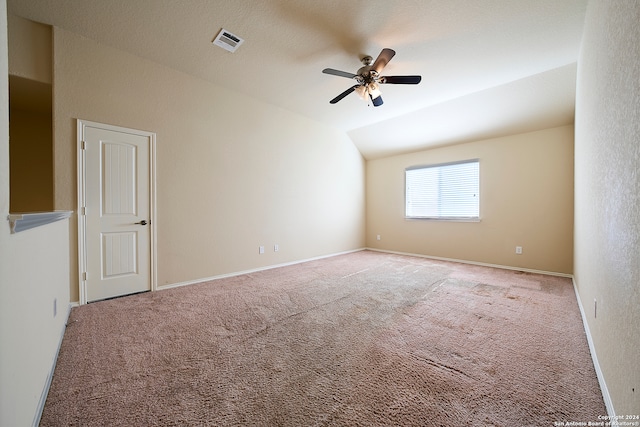 empty room featuring a textured ceiling, ceiling fan, light colored carpet, and lofted ceiling