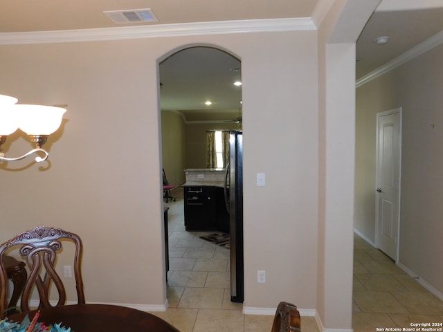 hall featuring light tile patterned floors, crown molding, and a chandelier