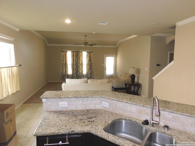 kitchen with light stone counters, ceiling fan, ornamental molding, and sink