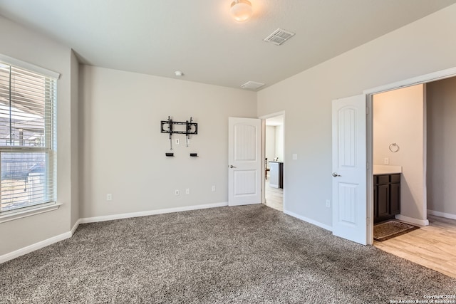 unfurnished bedroom featuring ensuite bath and carpet