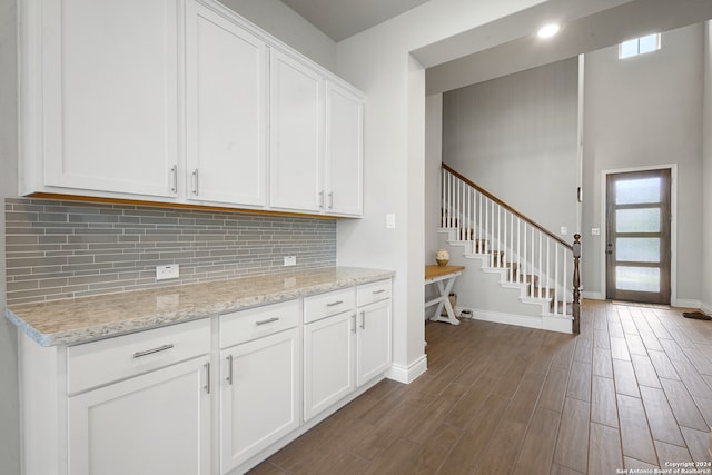 kitchen featuring white cabinets, dark hardwood / wood-style floors, light stone counters, and tasteful backsplash