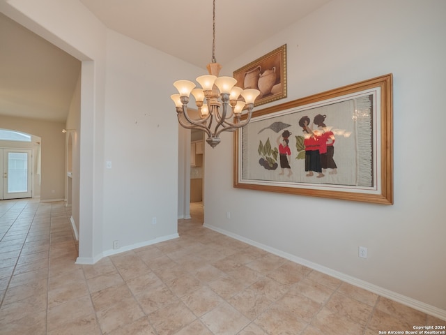 tiled empty room with vaulted ceiling and a notable chandelier