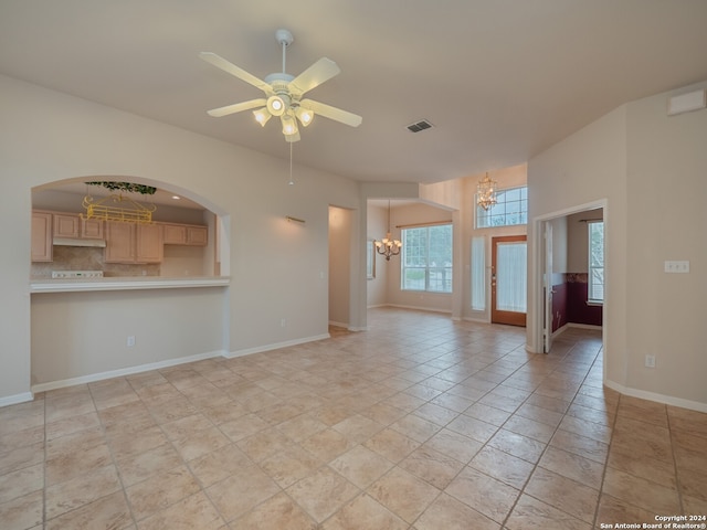 unfurnished living room featuring ceiling fan with notable chandelier and light tile patterned floors