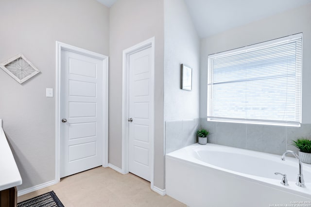 bathroom with a tub, tile patterned floors, and lofted ceiling