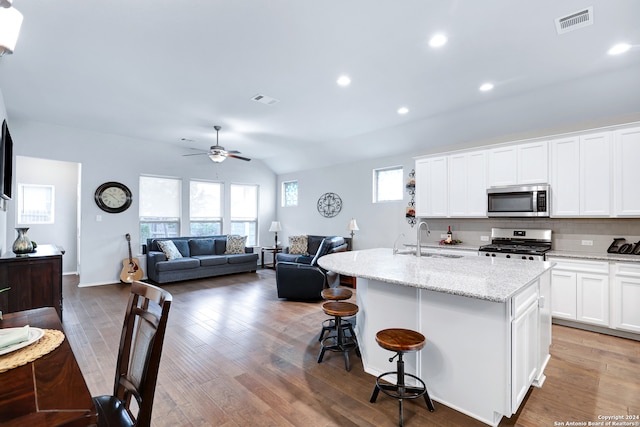 kitchen featuring wood-type flooring, a center island with sink, appliances with stainless steel finishes, sink, and white cabinets