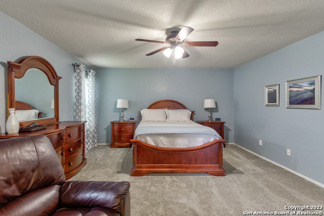 carpeted bedroom featuring ceiling fan and a textured ceiling