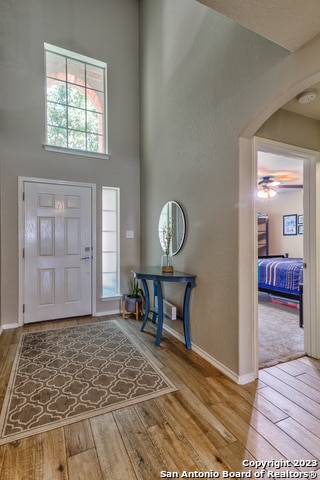 foyer entrance with a towering ceiling, hardwood / wood-style floors, and ceiling fan