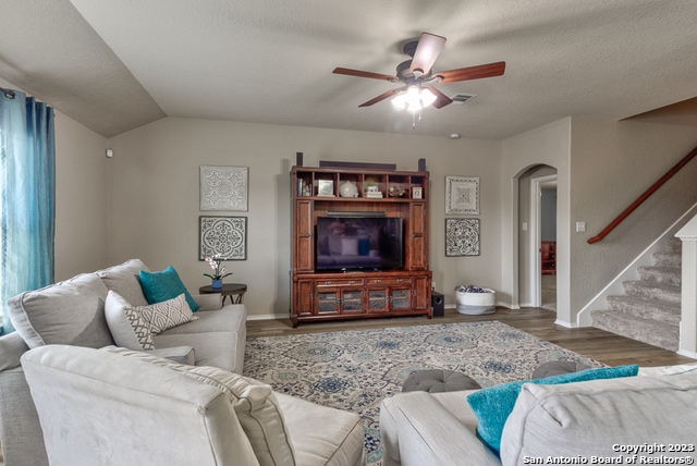 living room featuring a textured ceiling, dark hardwood / wood-style floors, ceiling fan, and vaulted ceiling