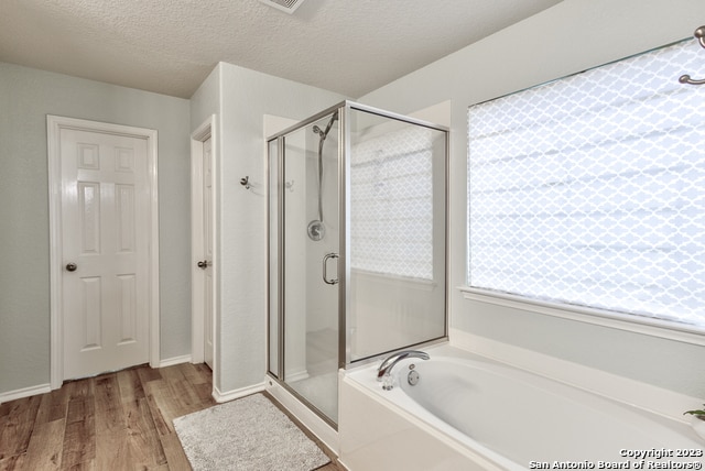 bathroom featuring wood-type flooring, a textured ceiling, and independent shower and bath