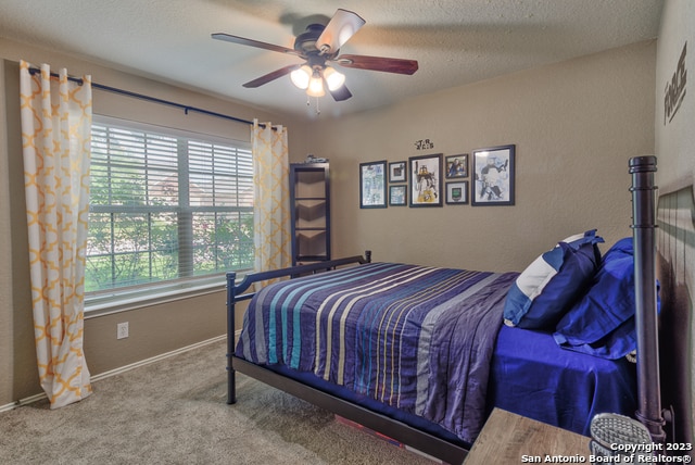 bedroom featuring a textured ceiling, ceiling fan, and carpet floors