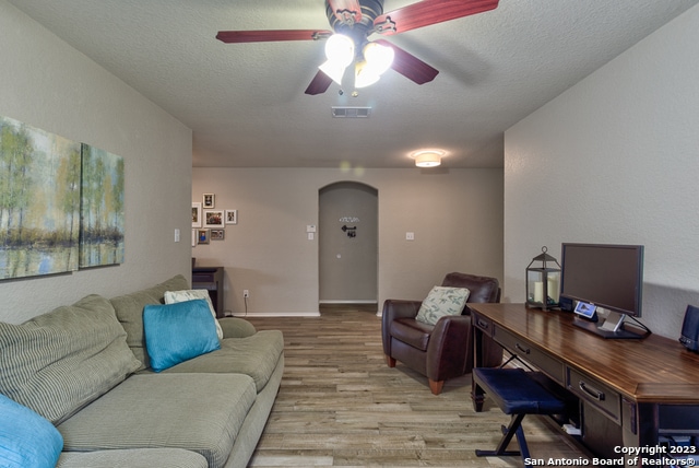 office with a textured ceiling, light wood-type flooring, and ceiling fan