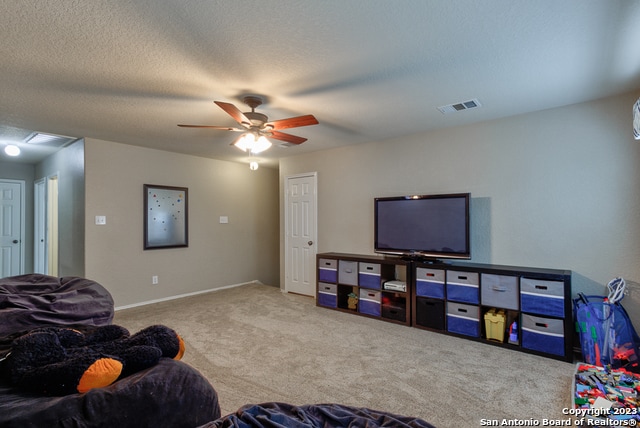 carpeted living room with a textured ceiling and ceiling fan