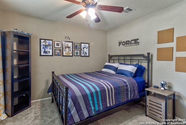 bedroom with a textured ceiling, carpet floors, and ceiling fan