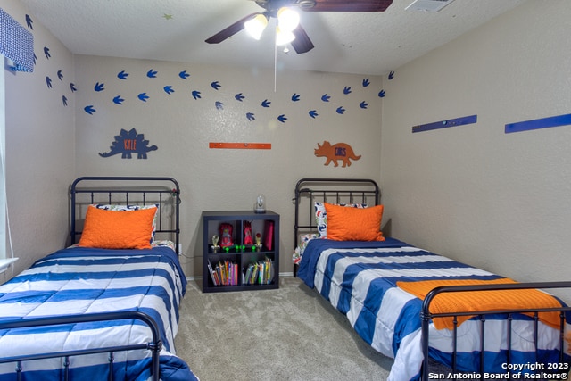 carpeted bedroom featuring ceiling fan and a textured ceiling