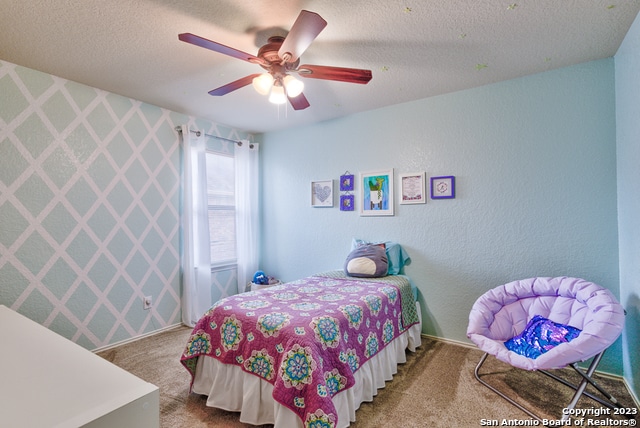 bedroom featuring carpet flooring, a textured ceiling, and ceiling fan