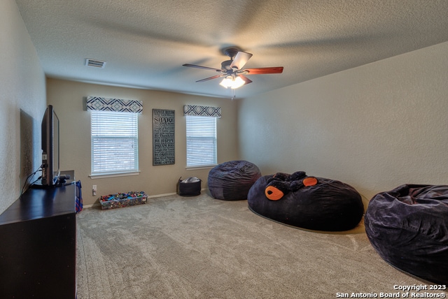 misc room with ceiling fan, a textured ceiling, and carpet