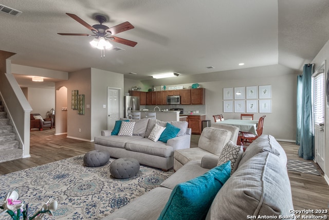 living room with a textured ceiling, dark hardwood / wood-style floors, and ceiling fan