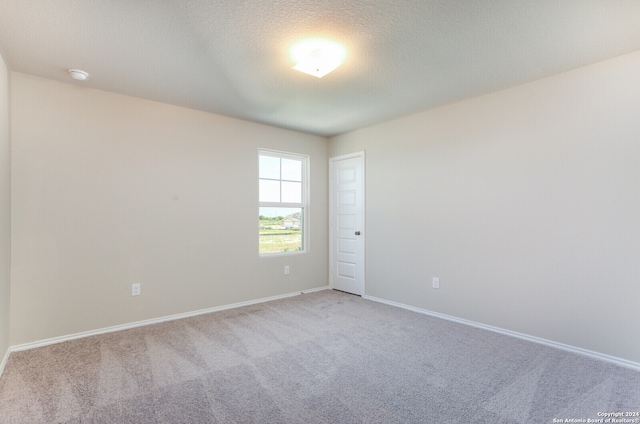 carpeted empty room featuring a textured ceiling