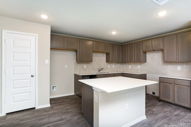 kitchen with tasteful backsplash, sink, dark hardwood / wood-style floors, and a center island