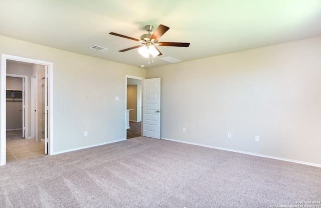 unfurnished bedroom with ceiling fan, light carpet, a closet, and a spacious closet