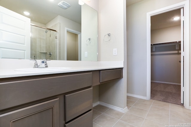 bathroom with walk in shower, vanity, and tile patterned floors