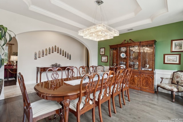 dining area featuring a tray ceiling, wood-type flooring, and a notable chandelier