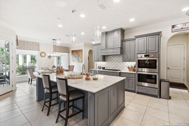 kitchen featuring gray cabinetry, hanging light fixtures, a large island, and stainless steel appliances