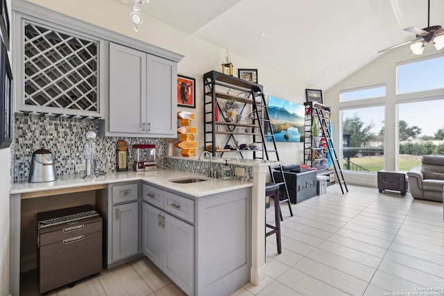 kitchen with kitchen peninsula, sink, tasteful backsplash, gray cabinetry, and light tile patterned floors