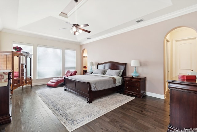 bedroom with dark hardwood / wood-style flooring, crown molding, ceiling fan, and a raised ceiling