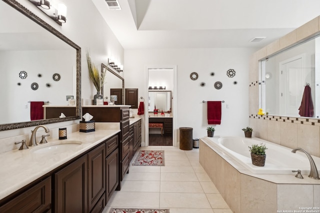 bathroom with vanity, a relaxing tiled tub, and tile patterned floors