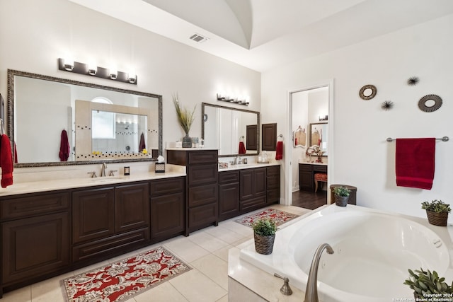 bathroom featuring a relaxing tiled tub, tile patterned flooring, vanity, and lofted ceiling