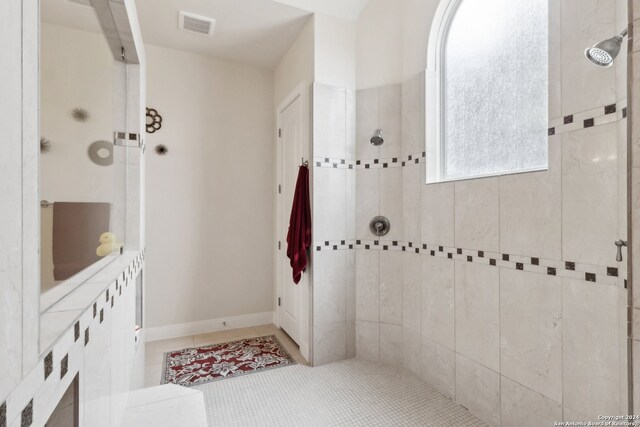 bathroom featuring tile patterned flooring and tiled shower