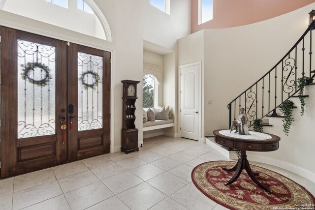 tiled entrance foyer with a high ceiling, french doors, and a healthy amount of sunlight