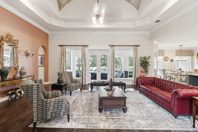 living room with ornamental molding, a chandelier, hardwood / wood-style flooring, and a raised ceiling