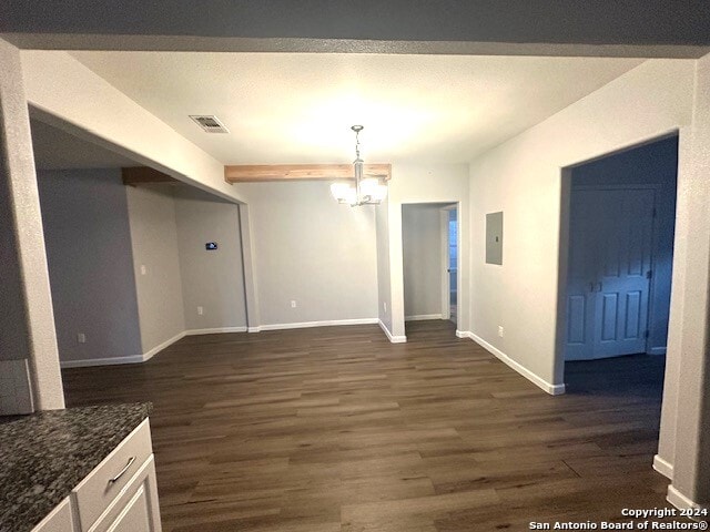 unfurnished dining area with dark wood-type flooring, electric panel, and a chandelier