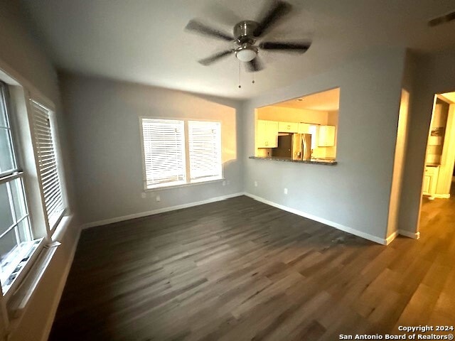 unfurnished living room with dark hardwood / wood-style floors and ceiling fan