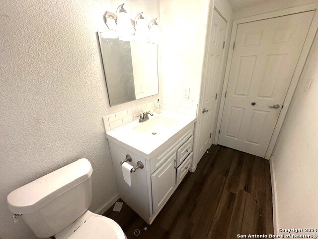 bathroom with hardwood / wood-style flooring, vanity, toilet, and tasteful backsplash