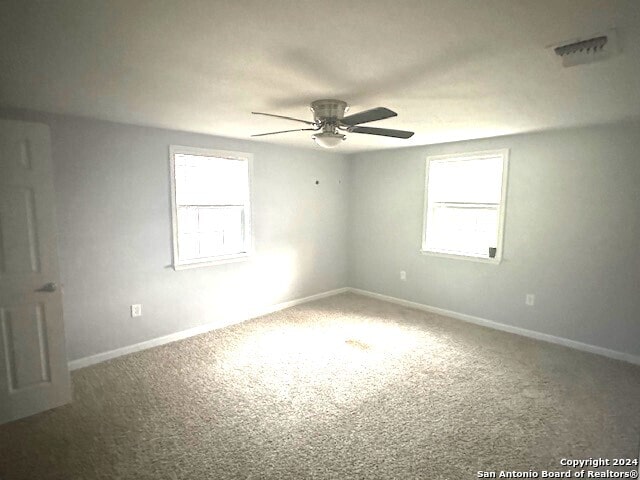 unfurnished room featuring a wealth of natural light, carpet floors, and ceiling fan