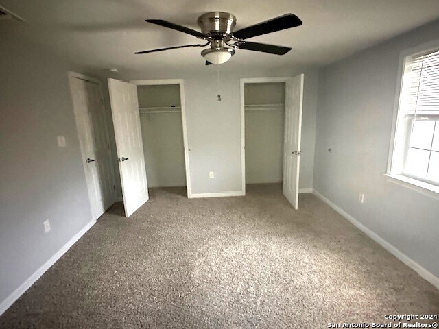 unfurnished bedroom with ceiling fan, two closets, and carpet floors