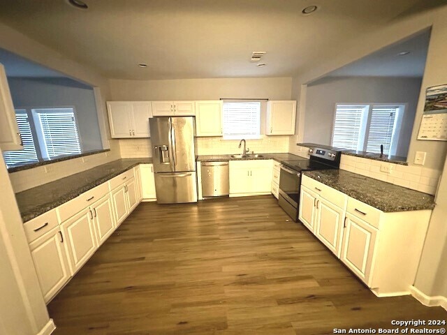 kitchen with stainless steel appliances, dark hardwood / wood-style floors, white cabinetry, and kitchen peninsula