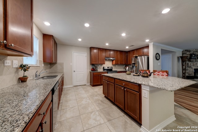 kitchen featuring a center island, sink, a breakfast bar area, light stone countertops, and appliances with stainless steel finishes