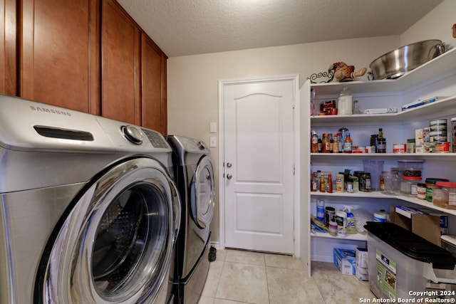 laundry room with cabinets, a textured ceiling, light tile patterned floors, and washing machine and clothes dryer