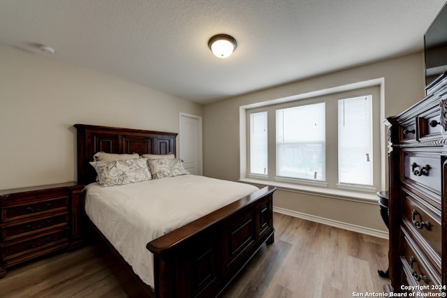 bedroom with hardwood / wood-style floors and a textured ceiling